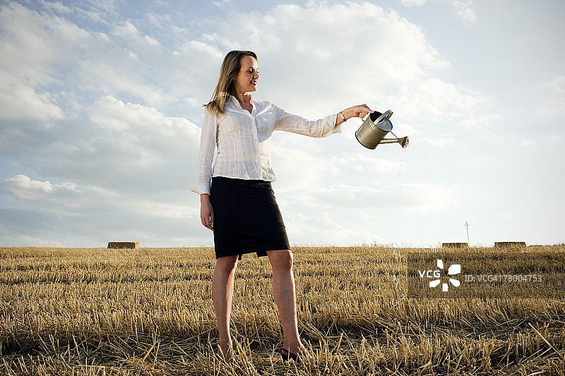 女人向麦田里倒水图片素材