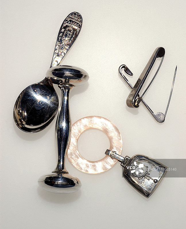 婴儿勺、两个婴儿摇铃和尿布别针特写图片素材