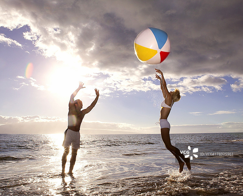 情侣在海滩上打沙滩排球图片素材