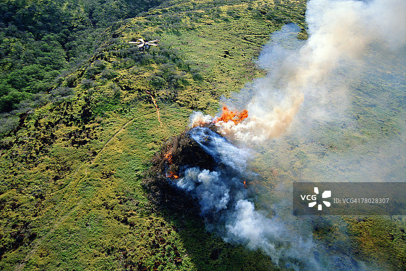 休斯500D直升机在卡胡拉韦岛附近使用火炬点燃大量枯树枝的航拍图片素材