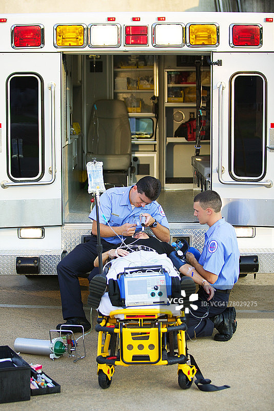 两名医护人员在救护车后部为担架上的病人插管图片素材