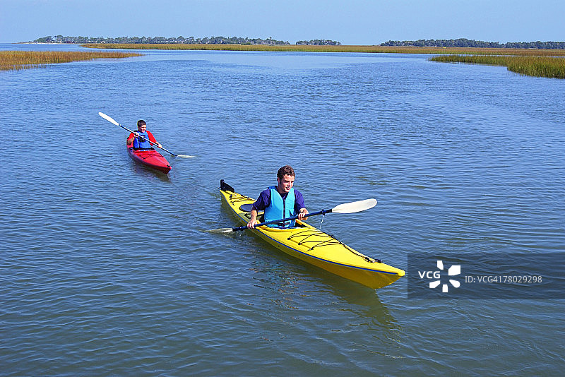 两个男孩在沼泽小溪中划皮划艇高角度拍摄图片素材
