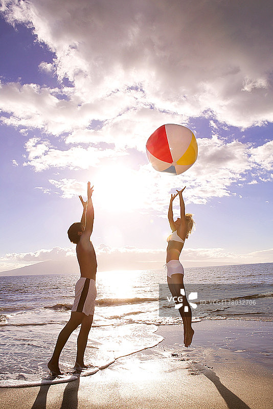 海滩情侣打沙滩球，女人跳跃图片素材
