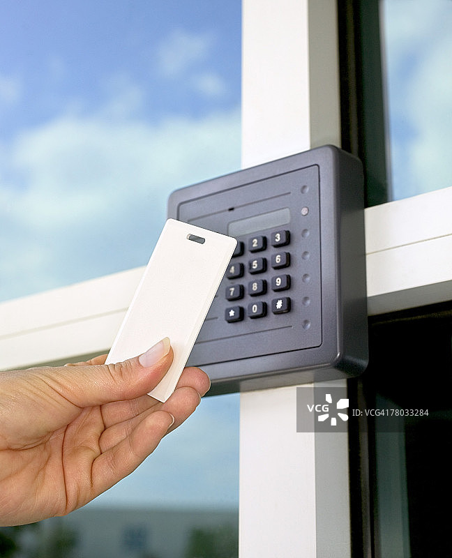 女人在安全大楼入口处用磁卡靠近安全键盘和读卡器的特写图片素材