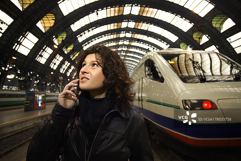 在意大利米兰中央火车站，站在火车旁，抬头用手机交谈的女人图片素材
