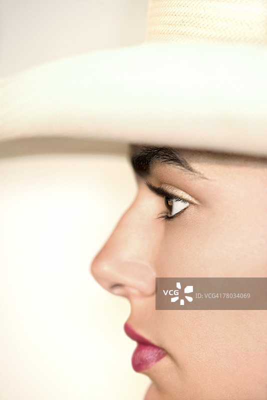 特写戴牛仔帽的年轻女人的侧面肖像。图片素材