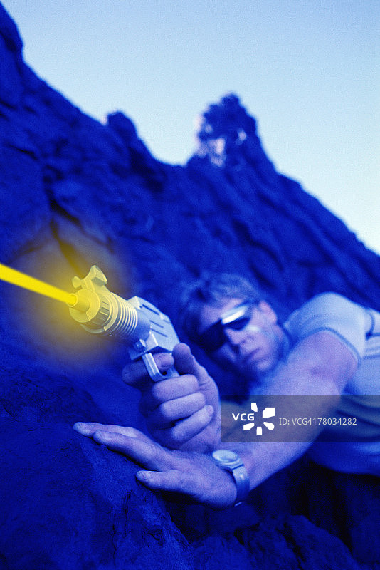 从岩石中射击激光枪的未来主义男人图片素材