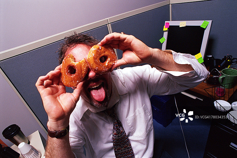 商人拿着甜甜圈当眼镜图片素材