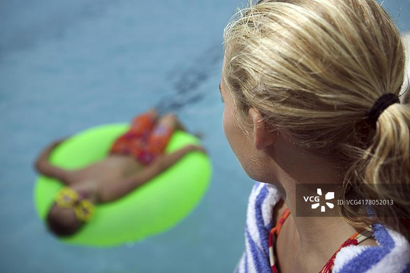 女孩看着游泳池里的哥哥图片素材