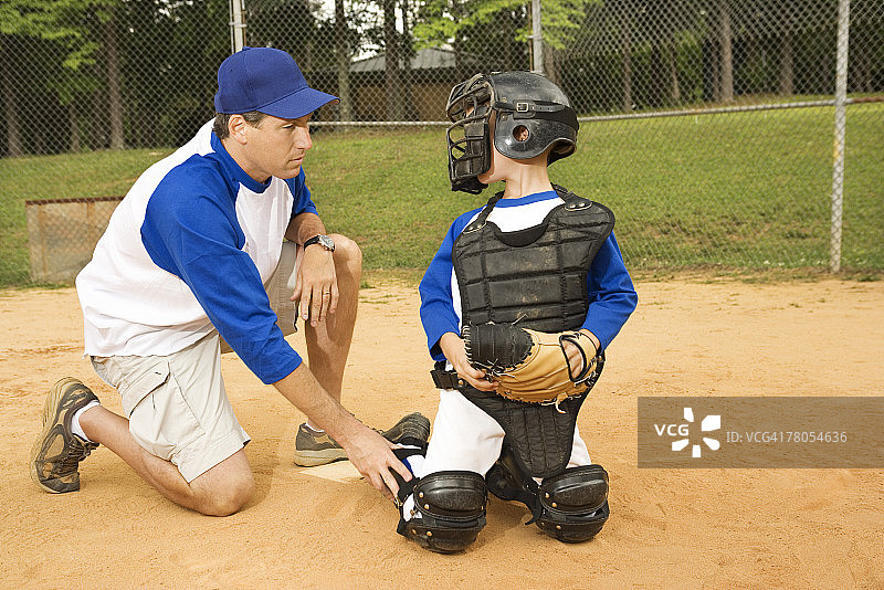 比赛期间教练与年轻棒球捕手交谈图片素材