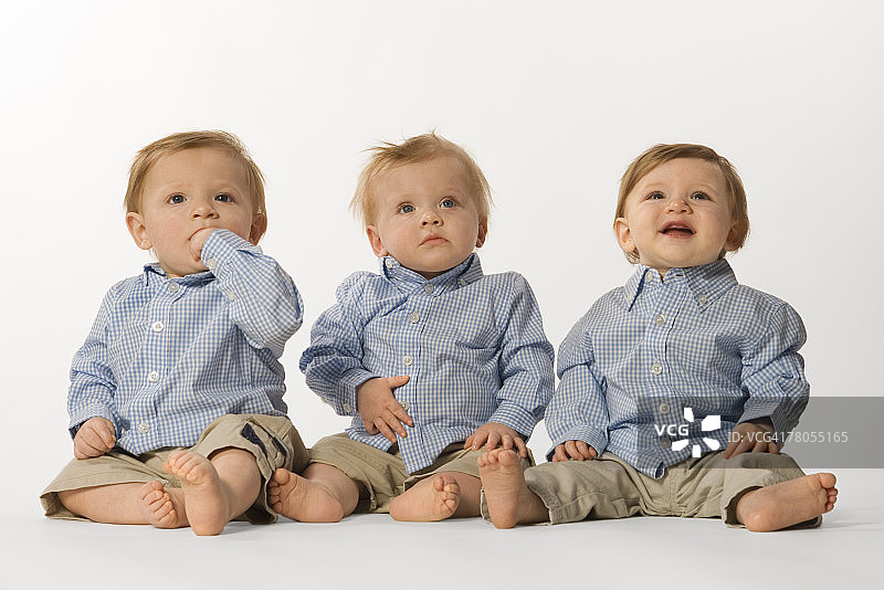 穿着纽扣衬衫坐着的三胞胎图片素材