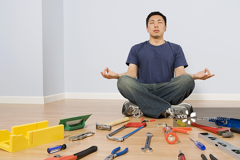 男子坐在地板上使用工具图片素材