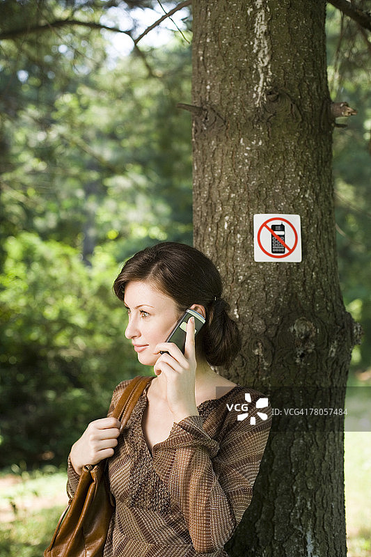 女人在禁止使用手机标志旁使用手机图片素材