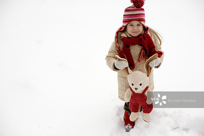 在雪地里抱着毛绒玩具的女孩图片素材