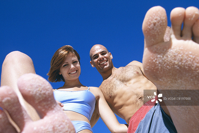 沙滩上脚踩细沙的情侣图片素材