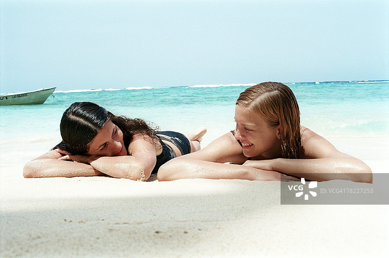 两个年轻女人躺在沙滩上晒日光浴图片素材