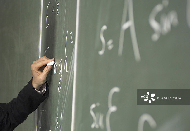 在黑板上书写公式的手部特写图片素材