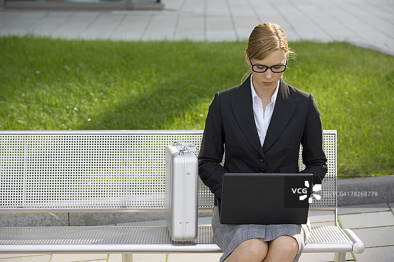 女商人坐在长椅上使用笔记本电脑图片素材