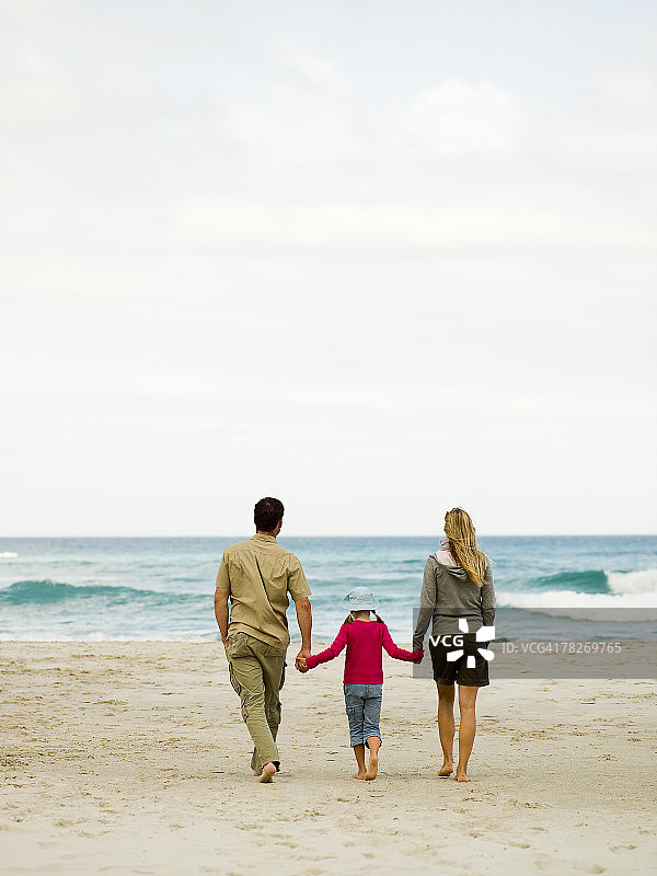 父母带着女儿在海滩上散步图片素材