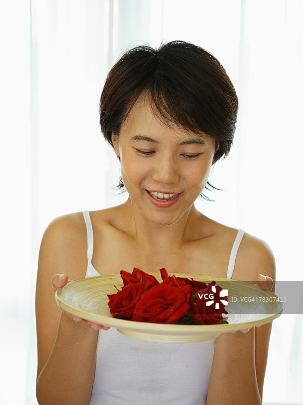 手持玫瑰花盘的年轻女子特写图片素材