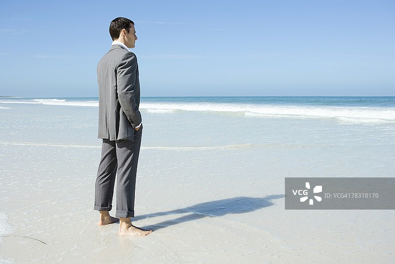 商人赤脚站在海滩上看风景图片素材