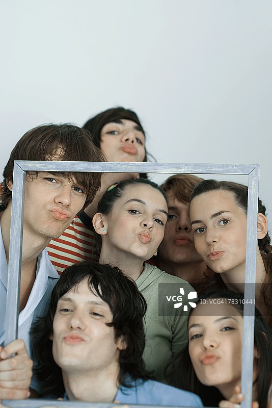 一群年轻朋友摆姿势拍照，举着相框，对着镜头撅嘴，肖像照图片素材