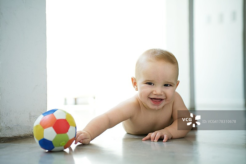 躺在地板上，拿着球，笑着看着镜头的宝宝图片素材