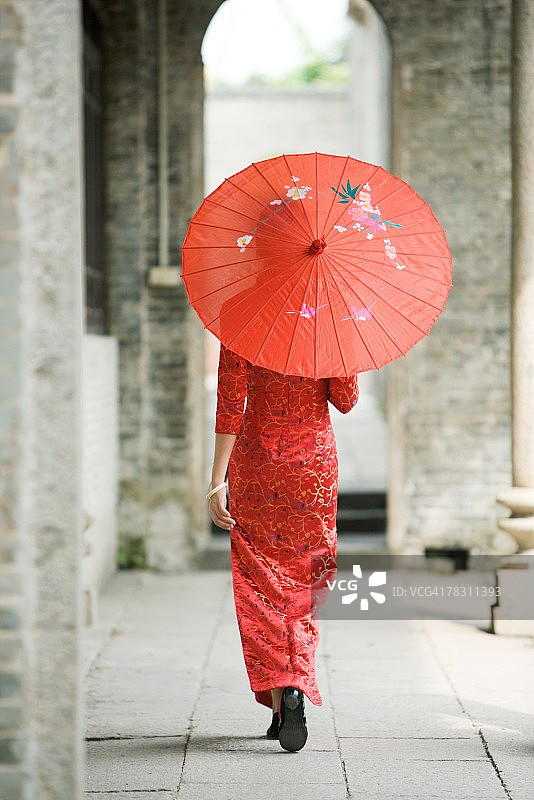 身穿中国传统服装，撑着阳伞行走的年轻女人（后视图）图片素材