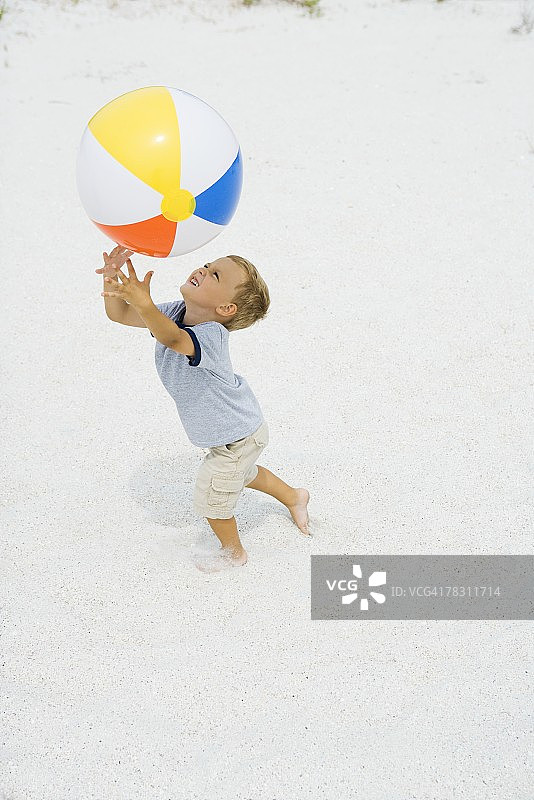 举起双臂接沙滩球的小男孩侧视图图片素材