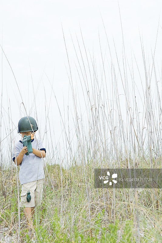 小男孩拿着玩具枪，假扮士兵看着镜头图片素材