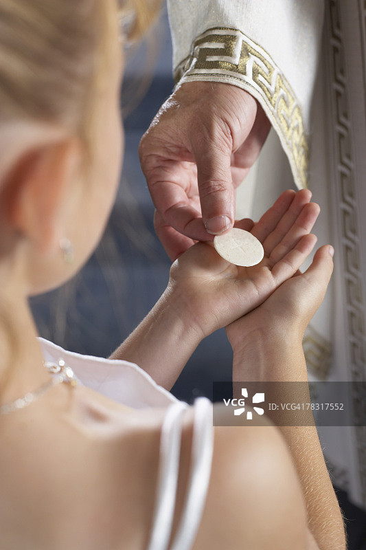 女孩从牧师手中领受圣餐图片素材
