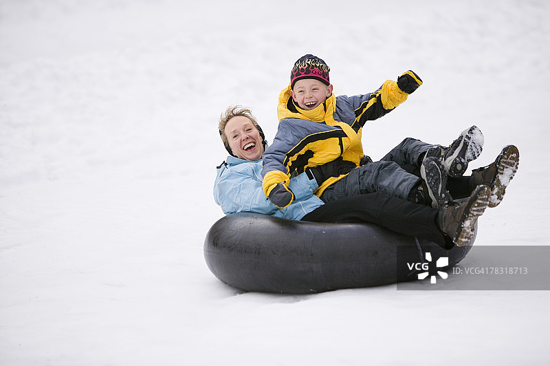 雪地里坐在内胎上的母子图片素材