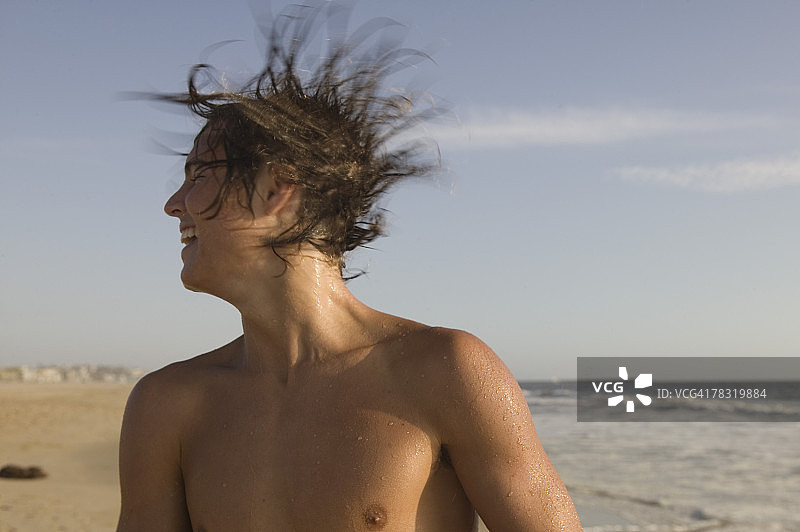 在海滩上甩头发的青少年男孩图片素材