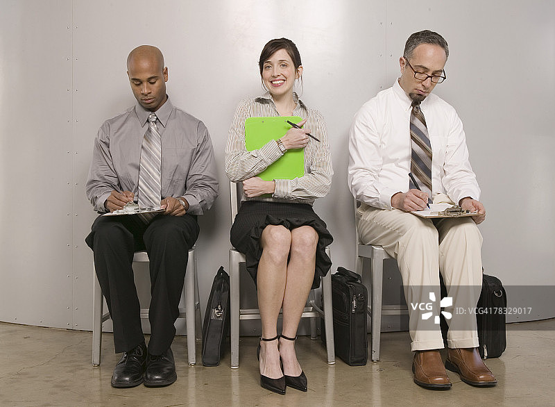 坐在填写申请表的男人中间的微笑女人图片素材