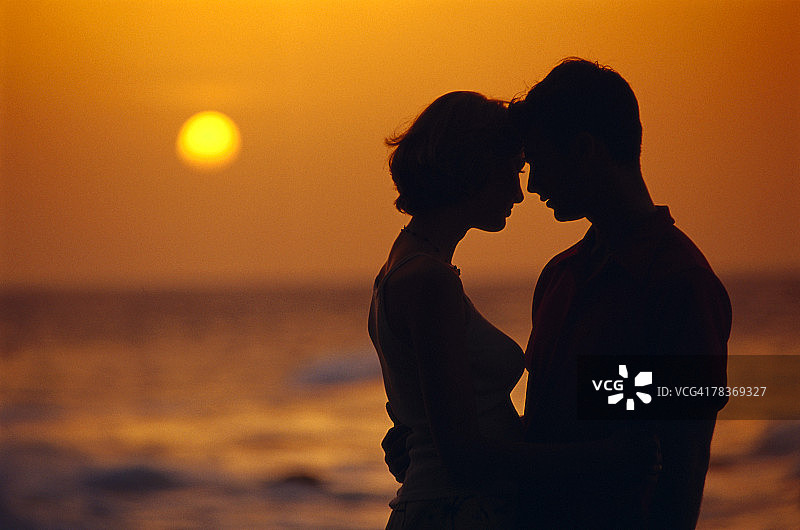 海滩日落下的男女剪影图片素材