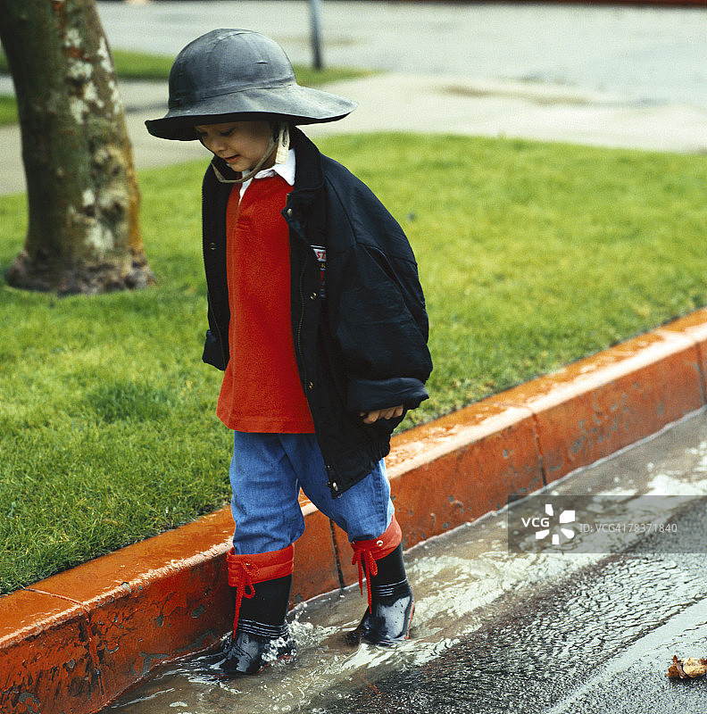 男孩在雨中水坑里行走图片素材