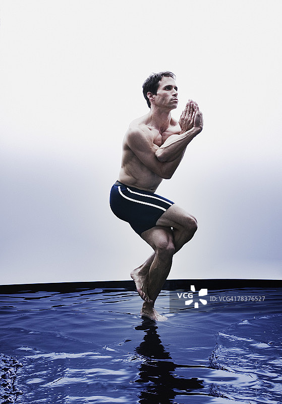 在水中做鹰式瑜伽的青年男子图片素材