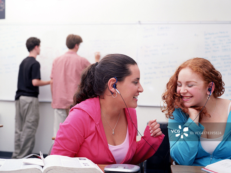 女孩们在课堂上戴着耳机听音乐图片素材