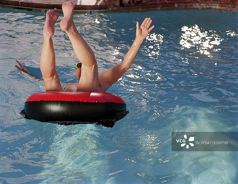 男人在游泳圈里跳入泳池图片素材