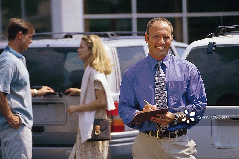 在售车场地，汽车销售员与一对夫妇图片素材