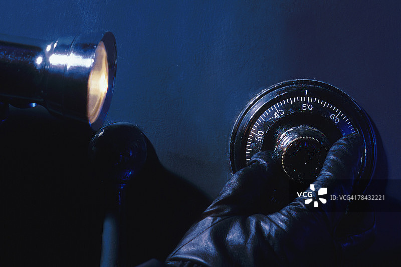 窃贼用手电筒撬保险箱图片素材