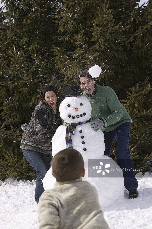 一家人与雪人一起打雪仗图片素材