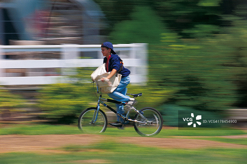 男孩在送报路线上骑自行车图片素材