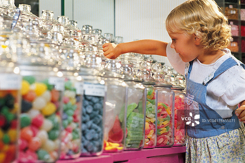 女孩在糖果店挑选糖果图片素材