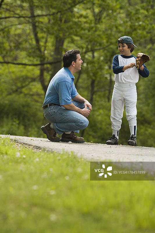男人和穿棒球服的男孩说话图片素材