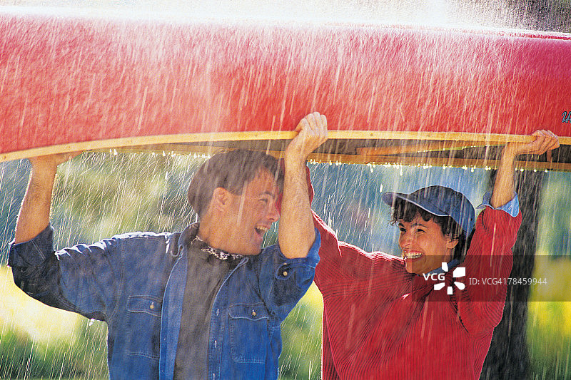 情侣在雨中扛着独木舟图片素材