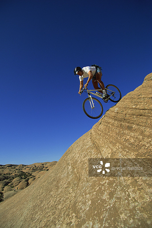 男子在光滑岩石小径上骑山地自行车图片素材
