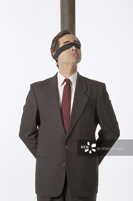 被绑在柱子上的蒙眼商人图片素材