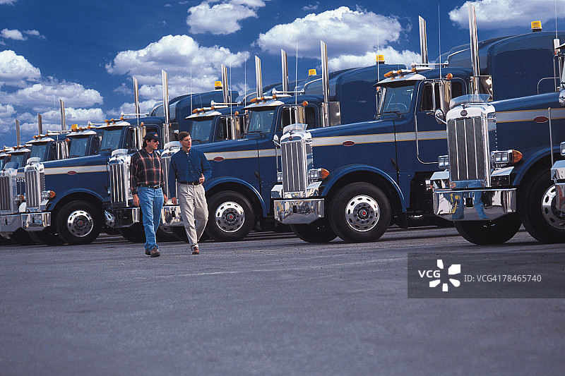 男人们走过一排半挂卡车图片素材