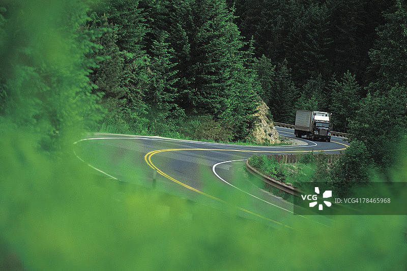 森林蜿蜒道路上的半挂卡车图片素材